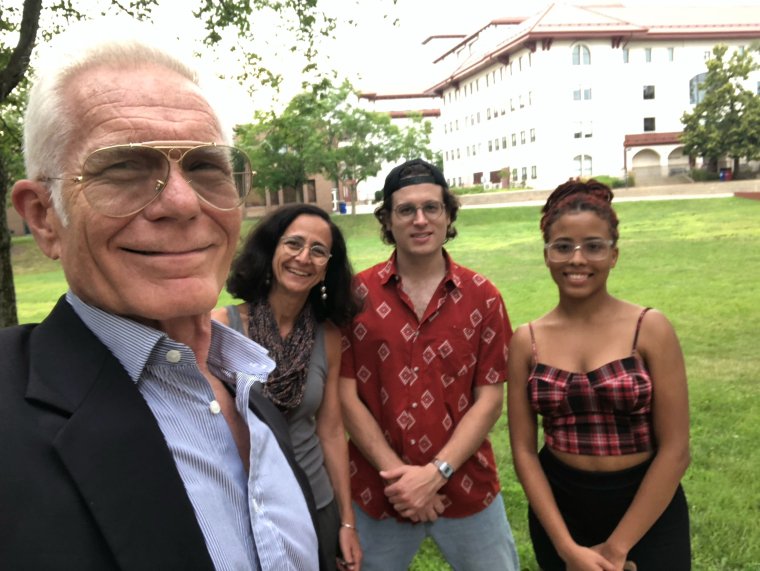 Four people pose for a photo outside on the campus of Montclair State University