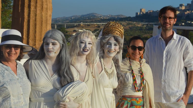 Three people pose with actors dressed in classical-era Greek attire
