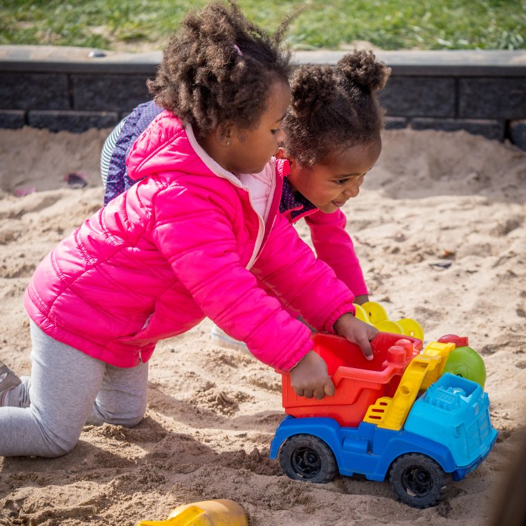 two students play in the sandbox